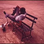Original caption: "Man Lounging on a Park Bench with His Radio on the Reis Park Boardwalk in New York City. 07/1974"